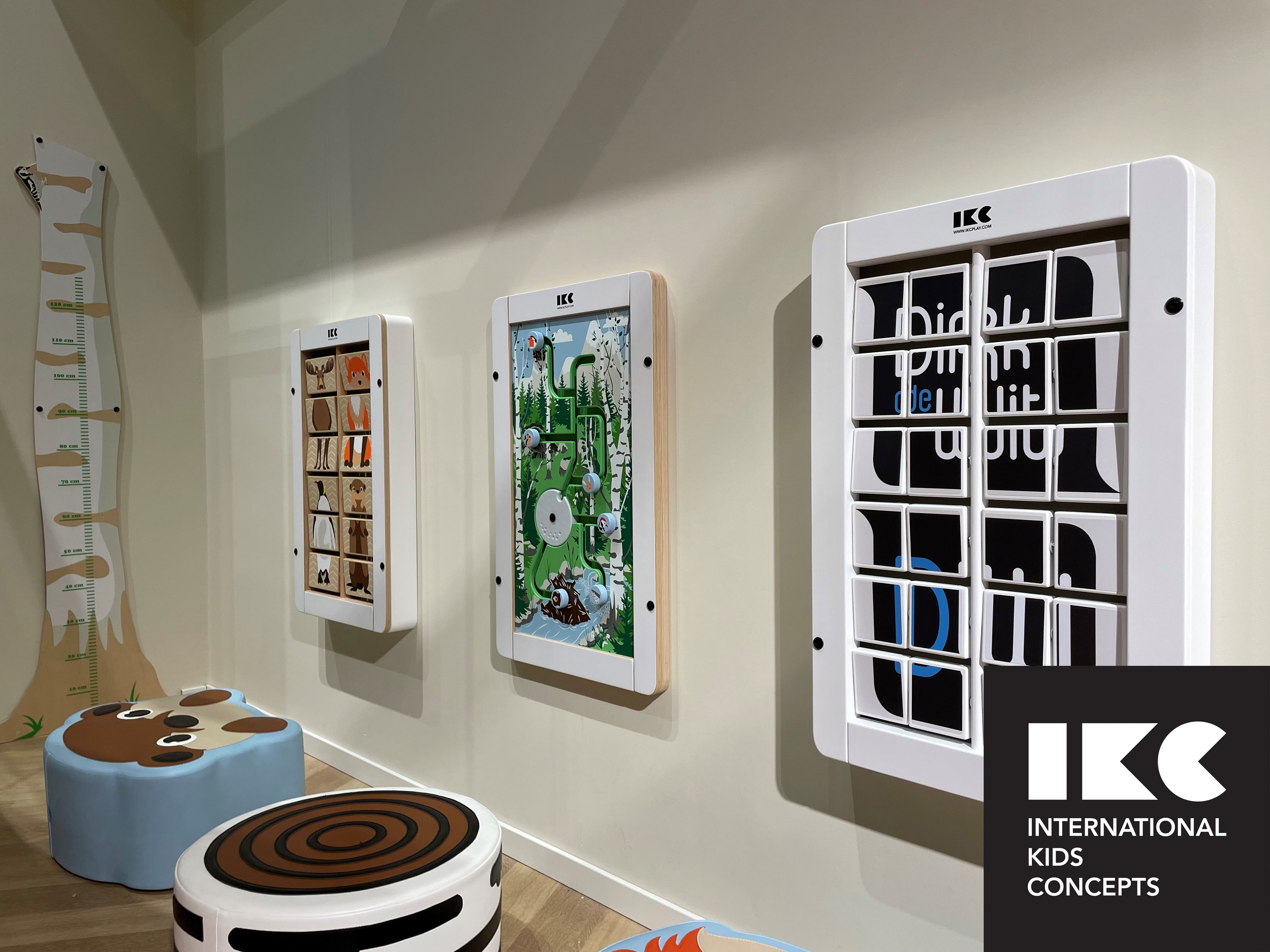 Children’s corner with interactive wall play panels and soft seating in a public waiting area