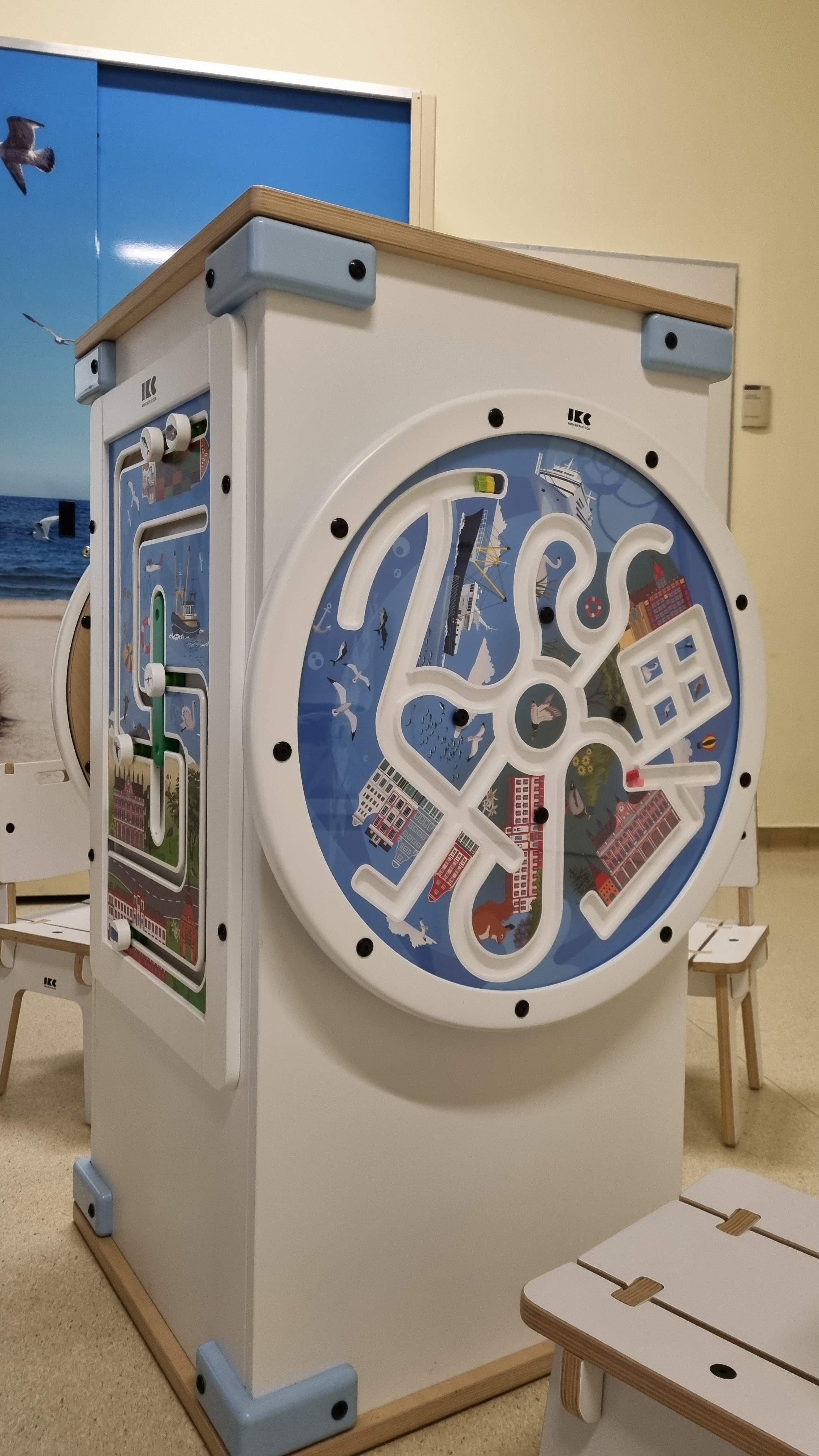 IKC speeltafel met groot rond doolhofspel en kleurrijke illustraties in de wachtruimte van Universitätsmedizin Rostock.