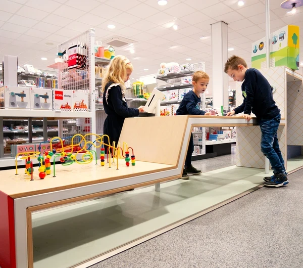 Kinderen spelen in een kleurrijke kinderhoek in een HEMA-winkel, ontworpen door IKC met houten speelelementen en educatief speelgoed.