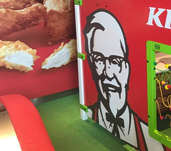 Kinderhoek bij KFC met een speelsysteem en interactieve speelwand, zodat kinderen veilig kunnen spelen terwijl ouders genieten van hun maaltijd.