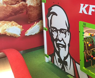 Kinderhoek bij KFC met een speelsysteem en interactieve speelwand, zodat kinderen veilig kunnen spelen terwijl ouders genieten van hun maaltijd.