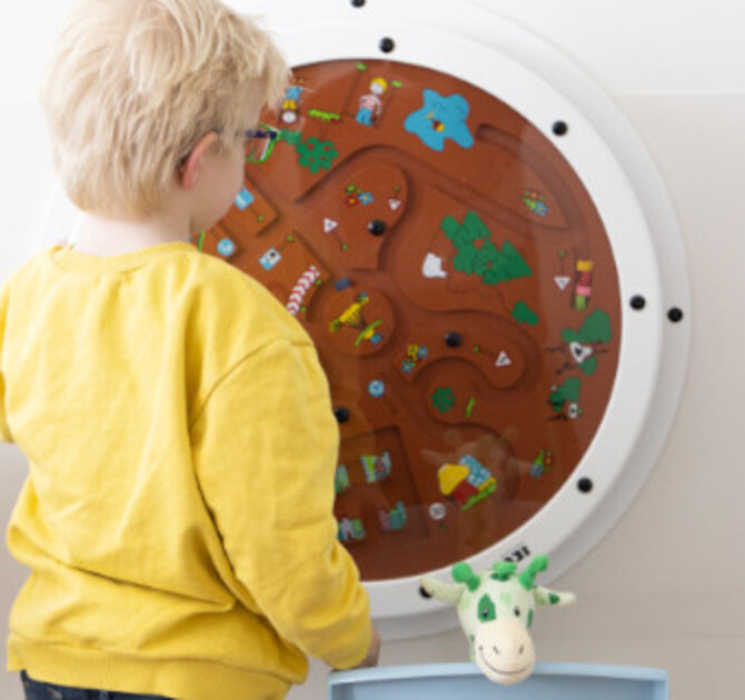 Kind speelt met wandspeelbord in de wachtkamer van het ziekenhuis