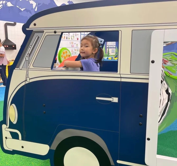 A young girl playing in a play system from IKC in the form of a van
